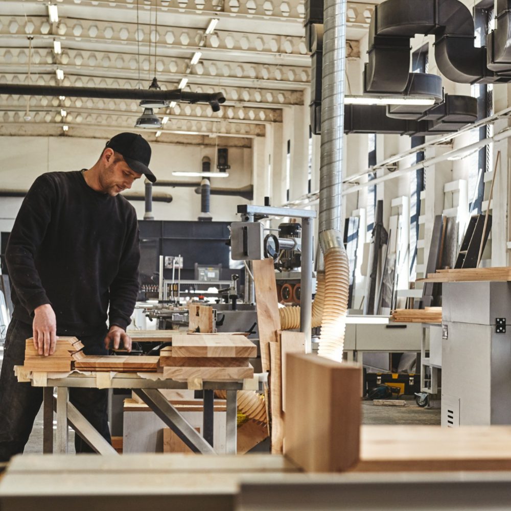 skilled-carpenter-black-uniform-cutting-piece-wood-his-woodwork-workshop skilled-carpenter-black-uniform-cutting-piece-wood-his-woodwork-workshop